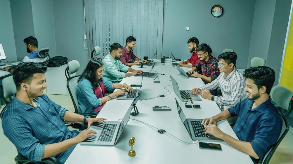 Eine Gruppe von Leuten, die mit Laptops an einem Tisch sitzen