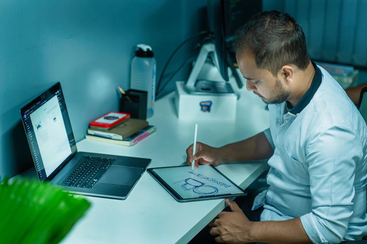 Consultant en chemise écrivant au stylet sur une tablette graphique posée sur bureau blanc, livrable sur mesure en cours