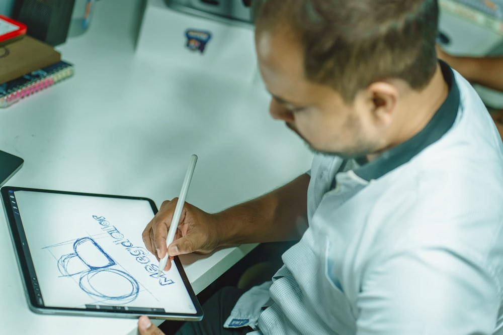 a man sitting at a desk drawing on a tablet