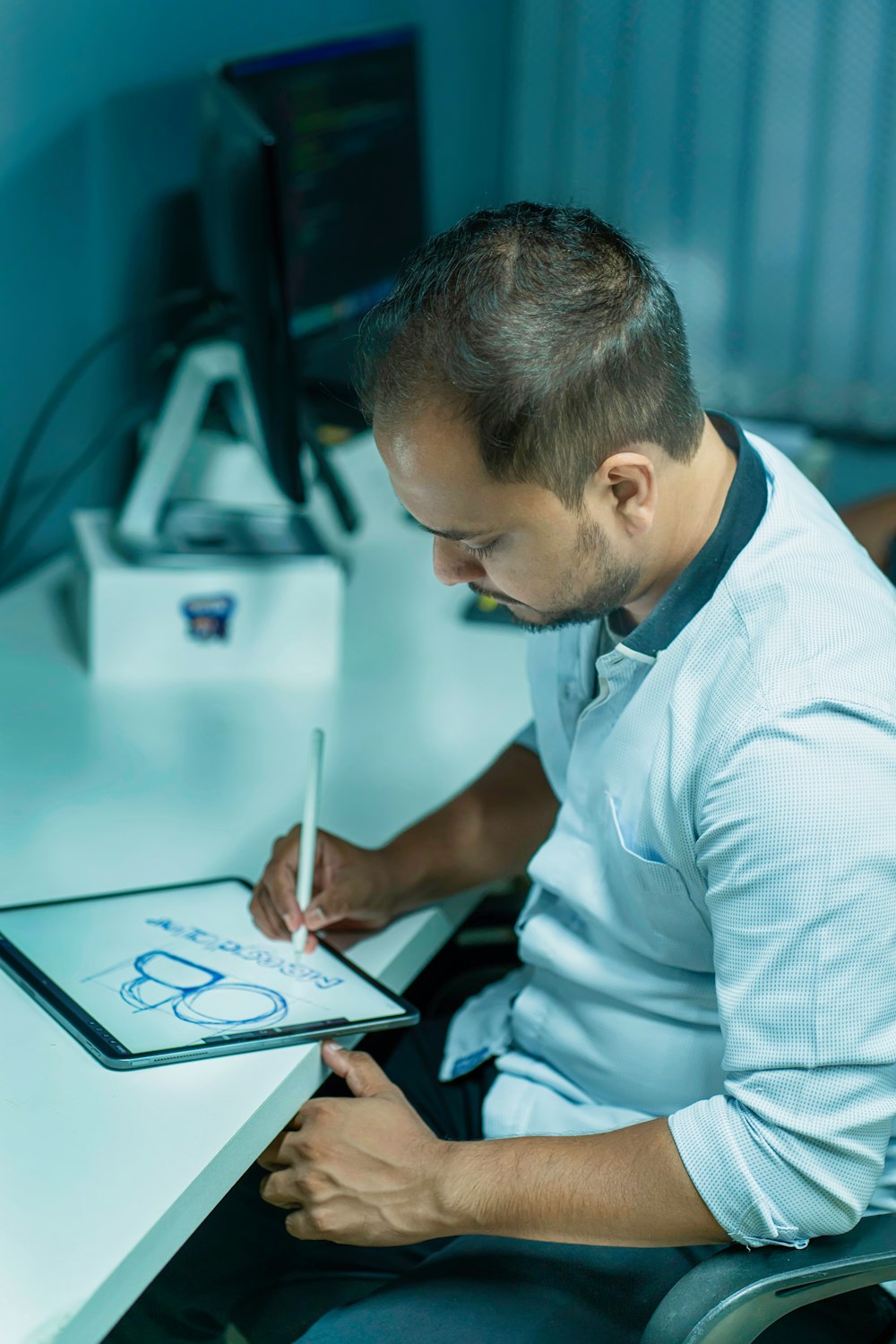 a man sitting at a desk writing on a tablet