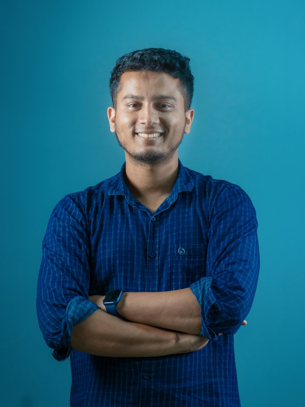 a man standing with his arms crossed in front of a blue background