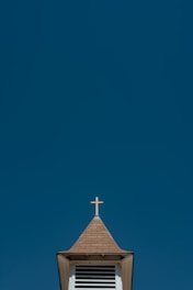A peaceful church steeple silhouetted against a clear blue sky.