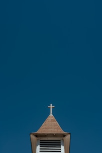 A peaceful church steeple silhouetted against a clear blue sky.