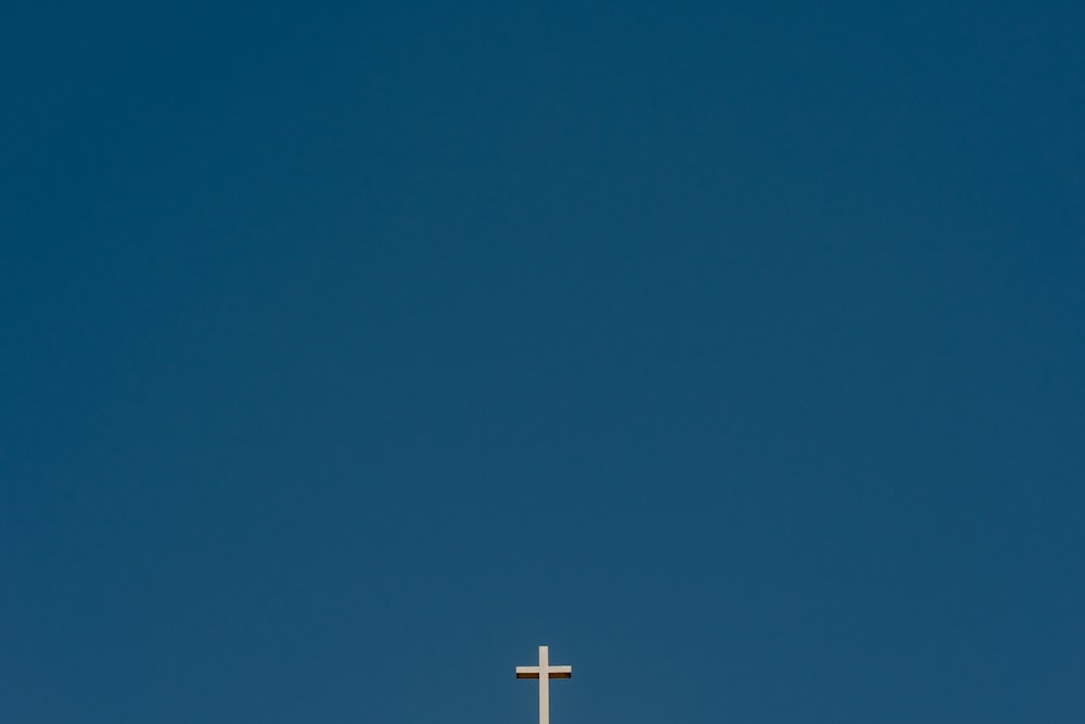 une croix au sommet d’un bâtiment avec un ciel bleu en arrière-plan