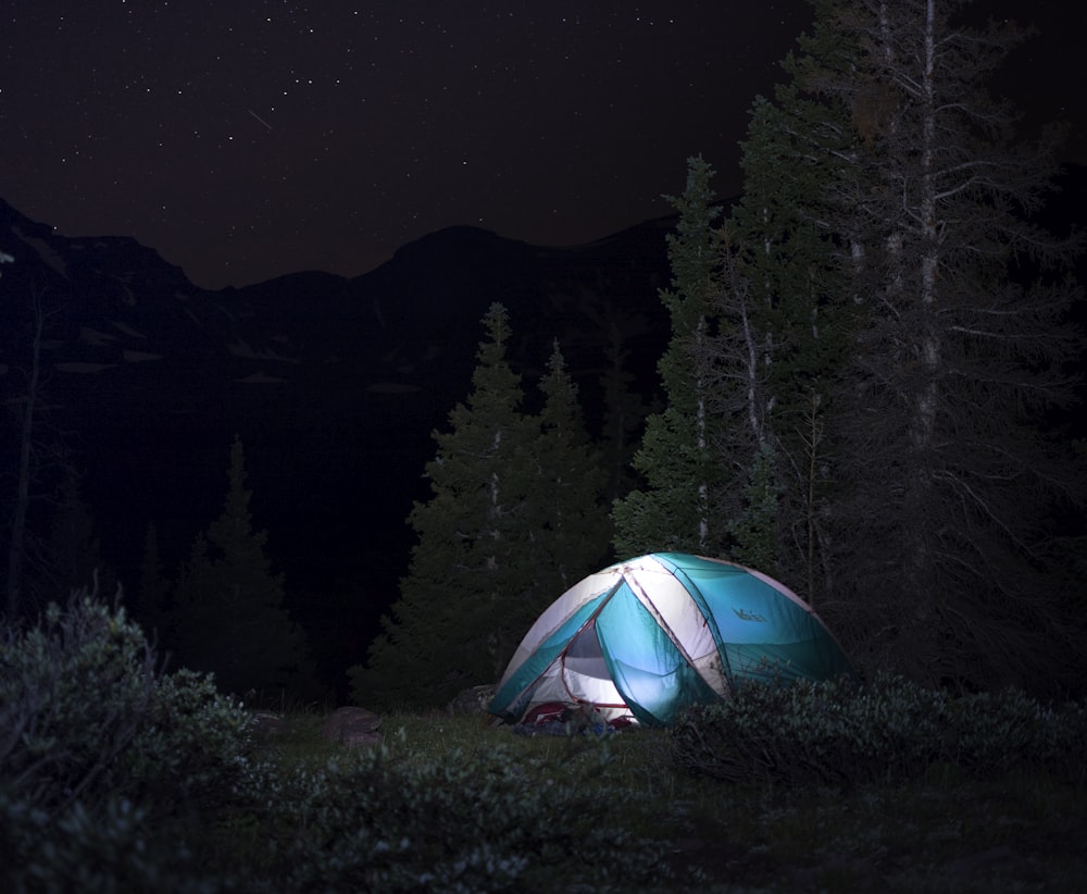 a tent pitched up in the woods at night