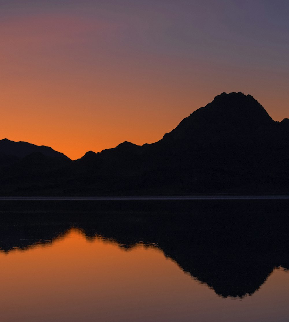 the sun is setting over a mountain range