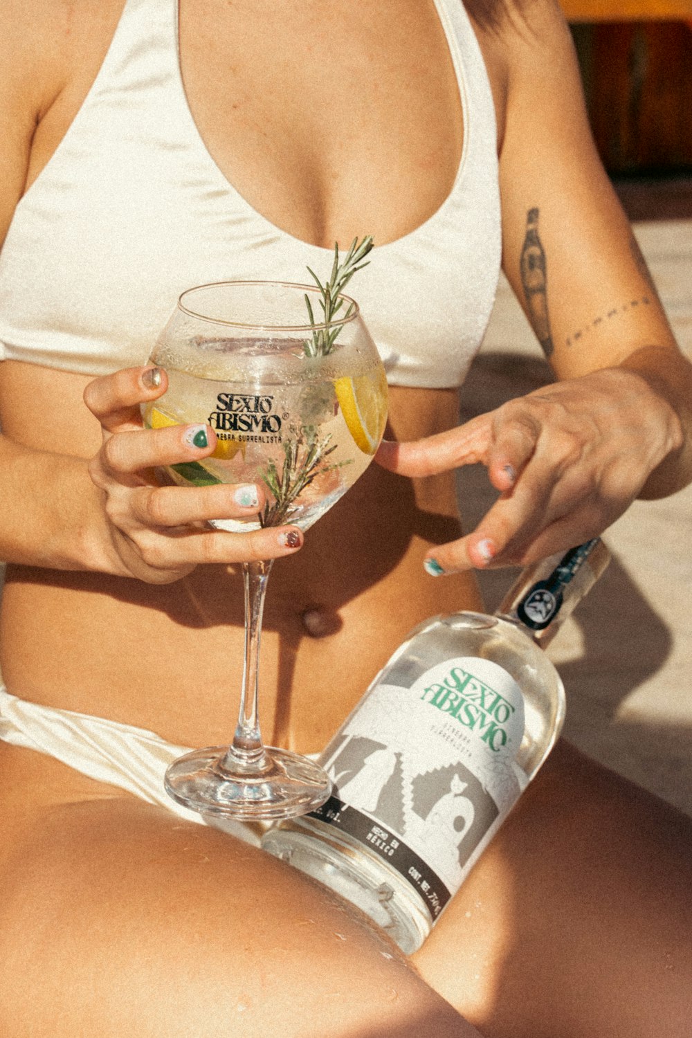 a woman in a bikini holding a glass of alcohol