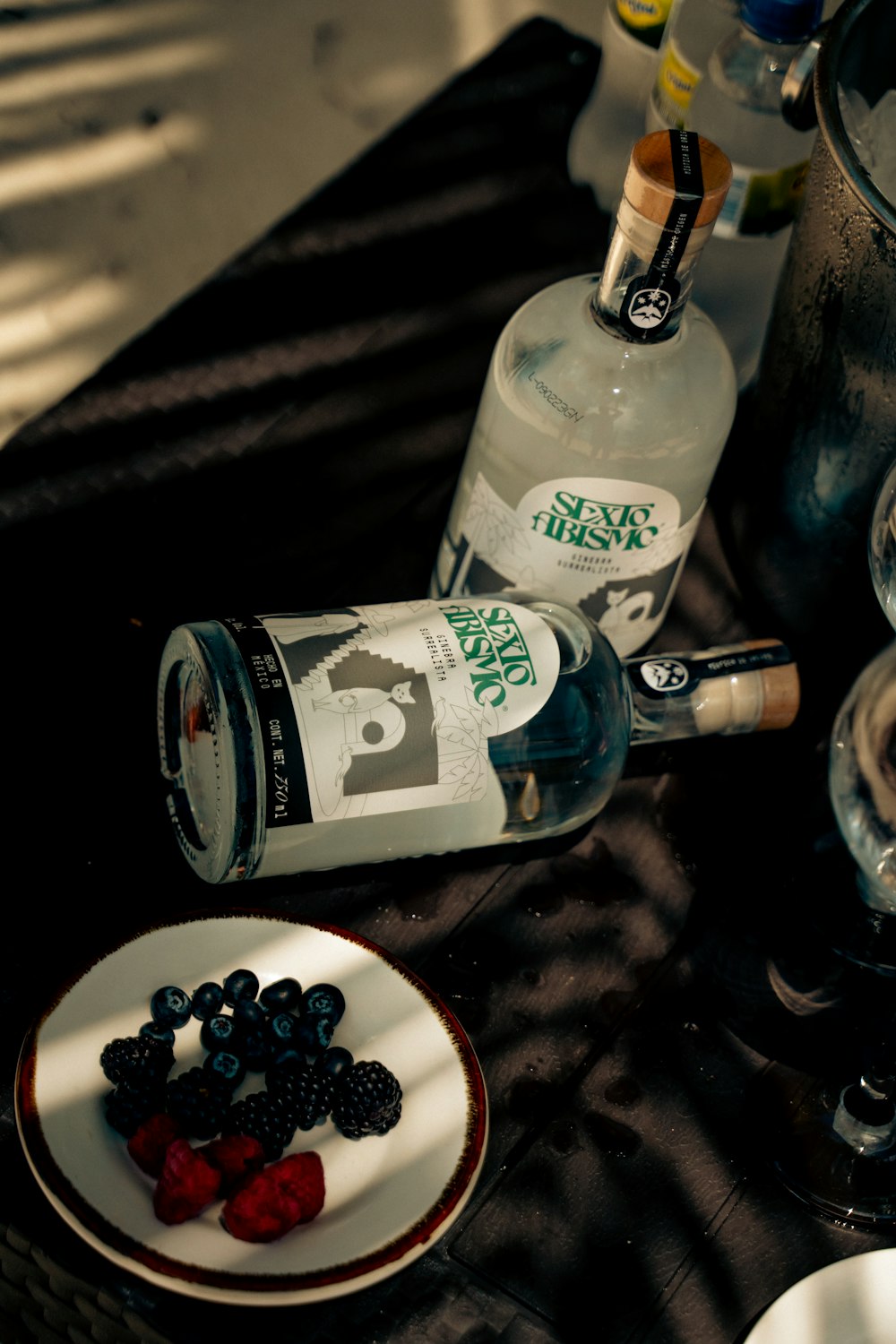 a plate of berries and a bottle of booze on a table