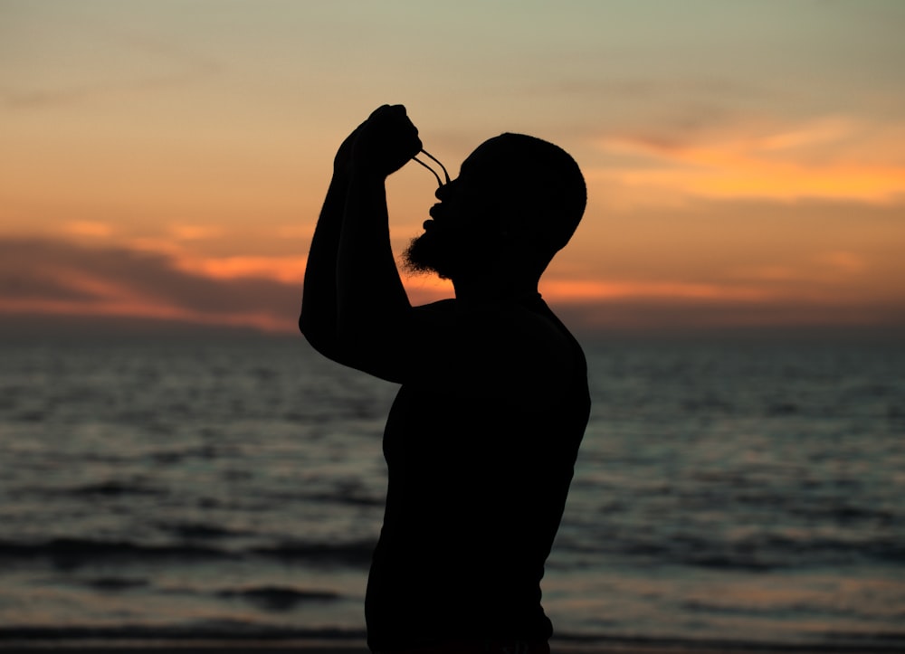 a silhouette of a man standing on a beach at sunset