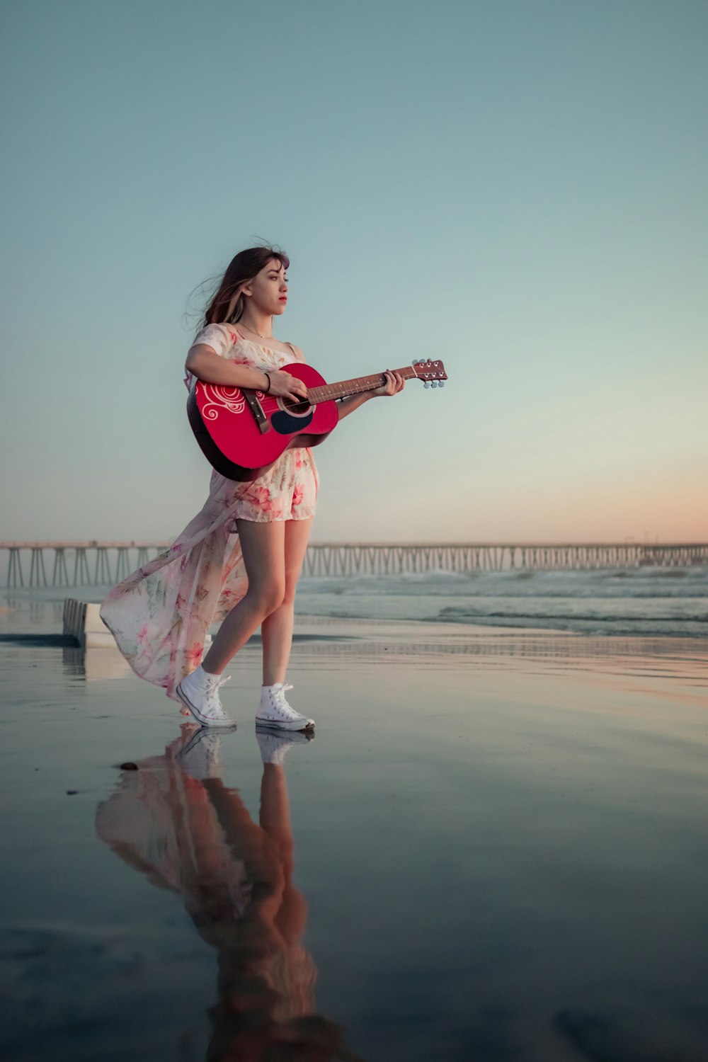 a woman is playing a guitar on the beach