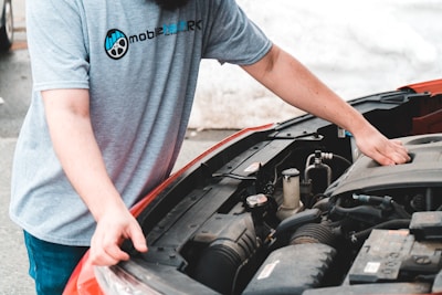 A skilled mechanic inspecting a car engine inside a clean, well-equipped auto repair shop.