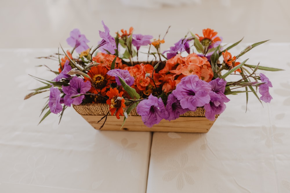 a wooden basket filled with purple and orange flowers