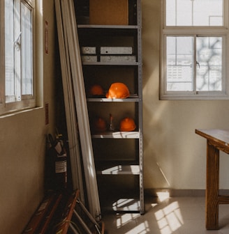 a room with a table and a shelf filled with oranges