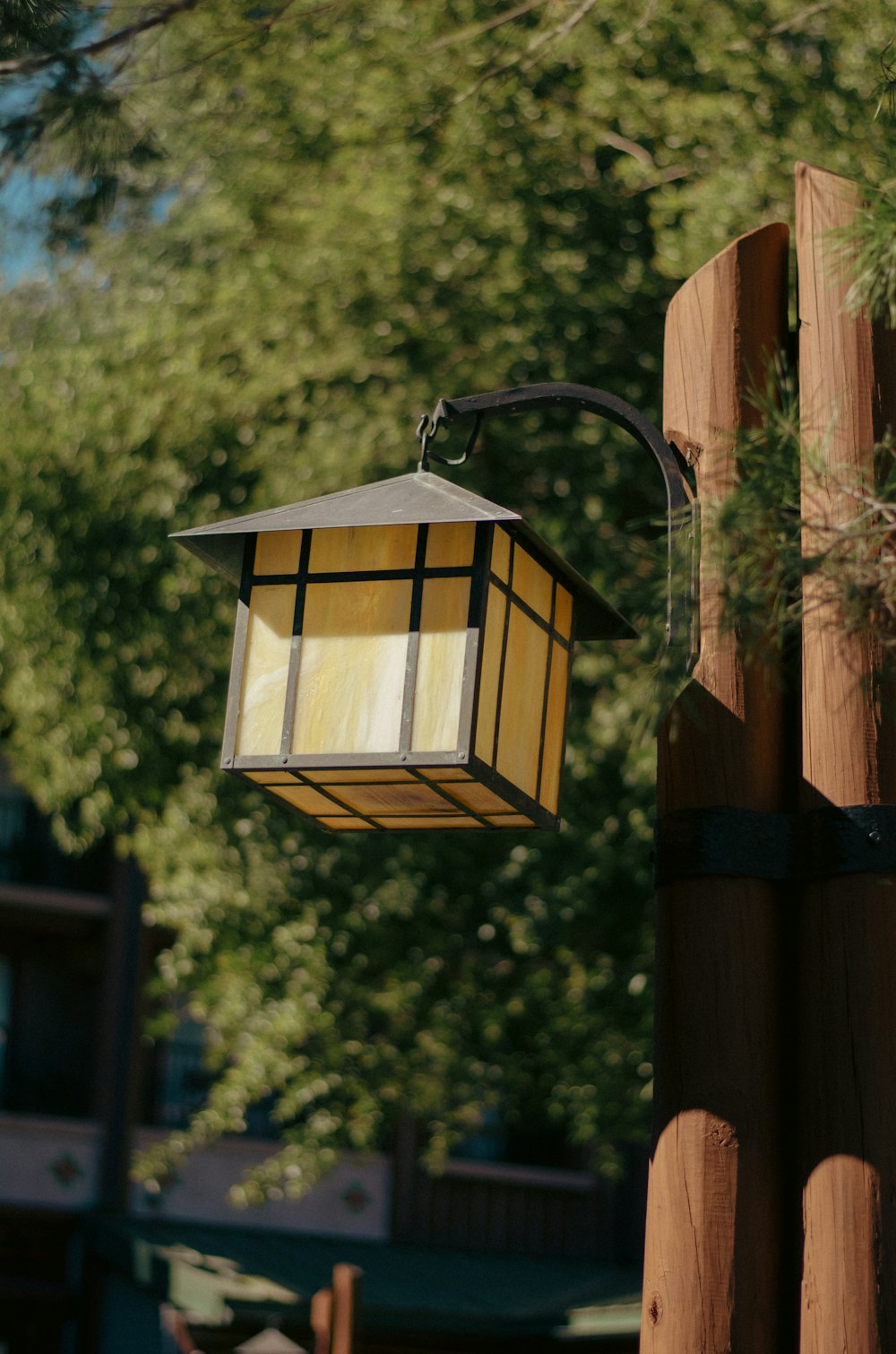 a lamp hanging from a wooden post next to a tree