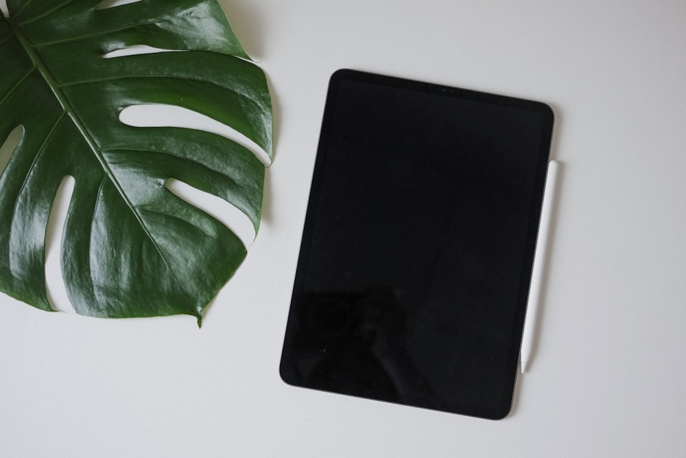 a cell phone sitting next to a green leaf