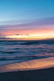 a sunset view of the ocean with a surfboard in the foreground