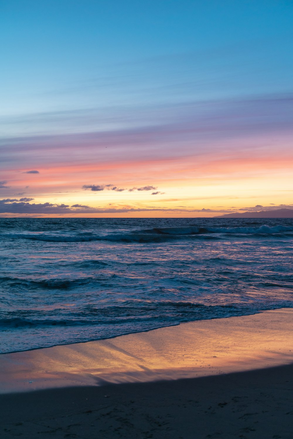 a sunset view of the ocean with a surfboard in the foreground