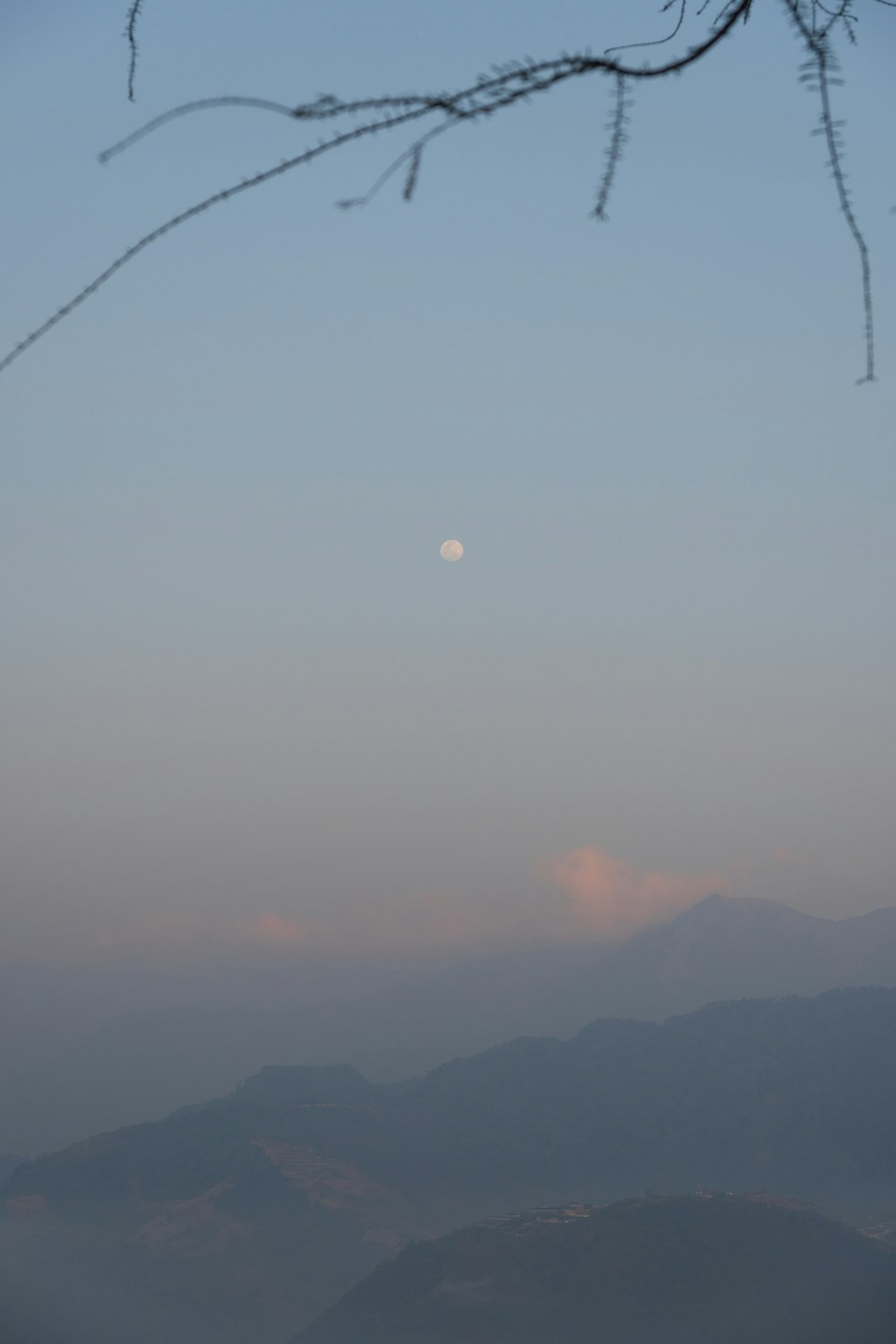 Una vista de una cordillera con luna llena en la distancia