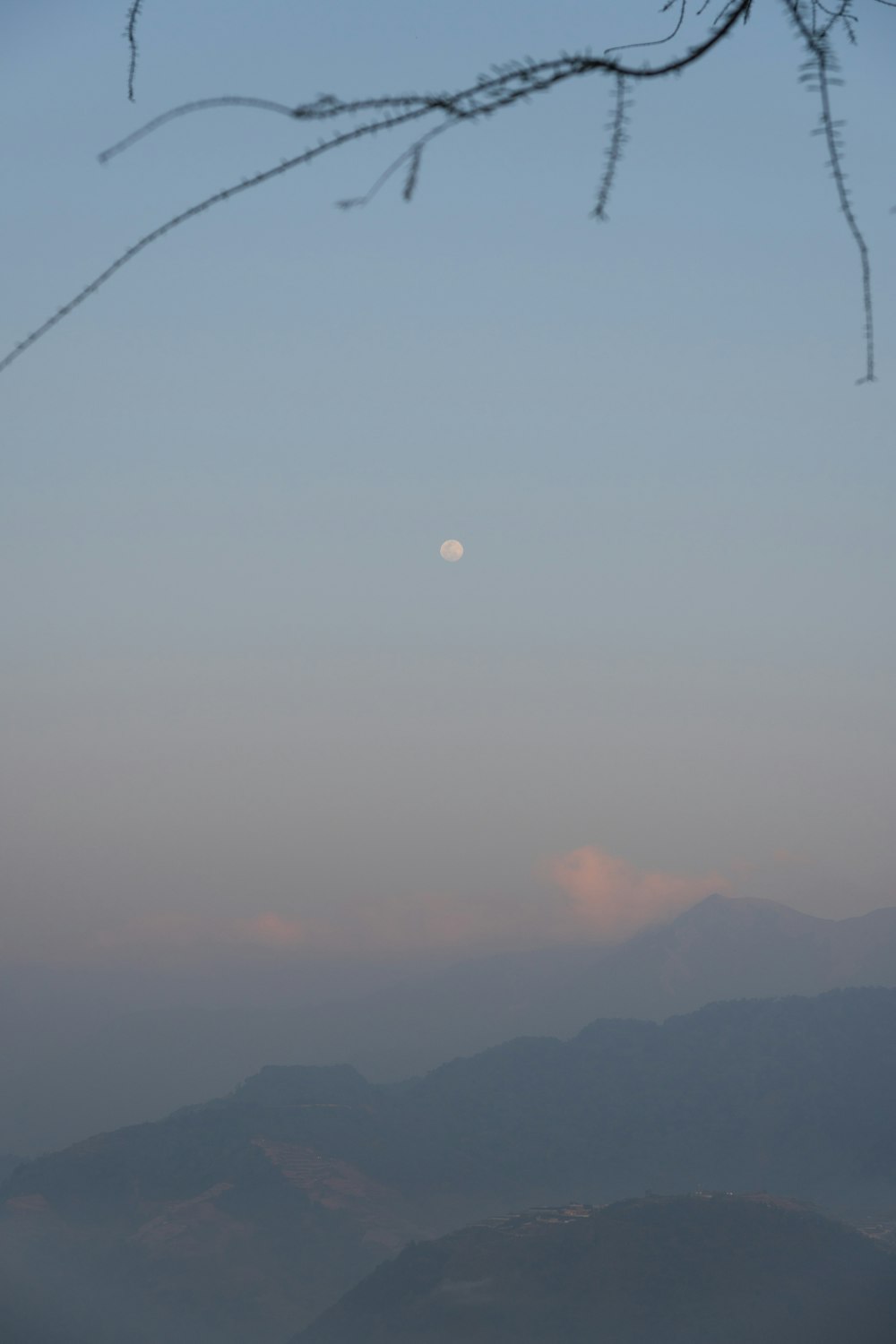 uma vista de uma cordilheira com uma lua cheia à distância