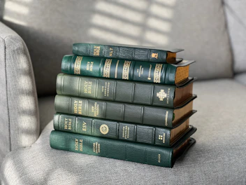 Stack of elegantly bound Bibles with soft natural lighting highlighting their details.