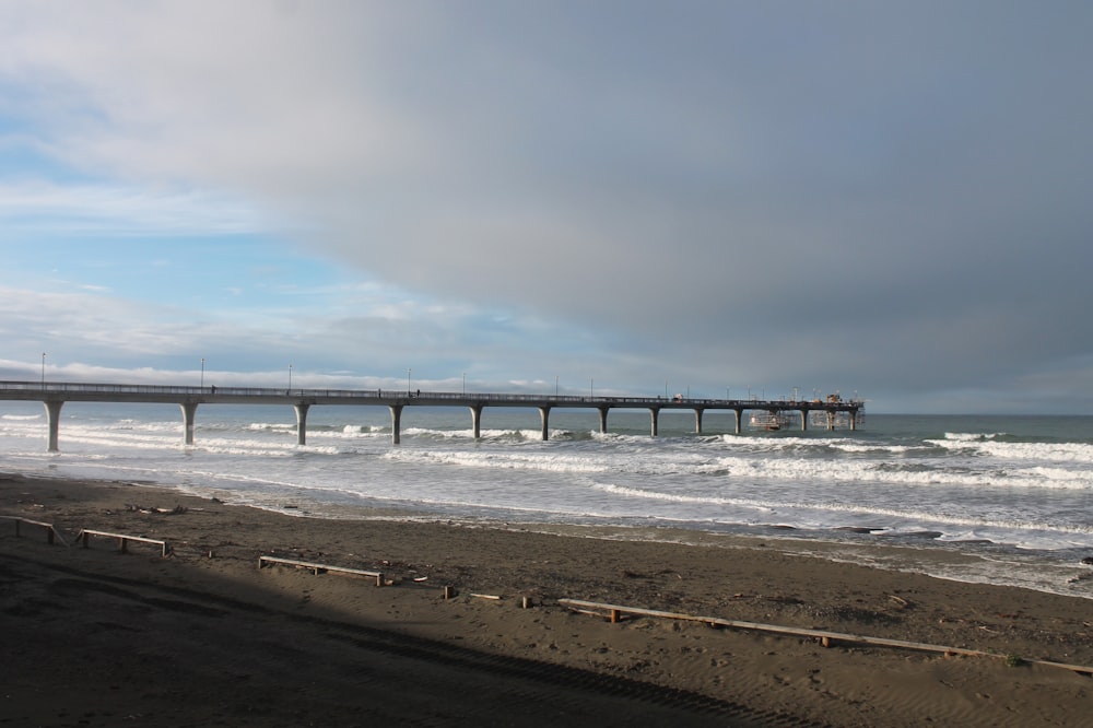 a beach with a pier in the distance