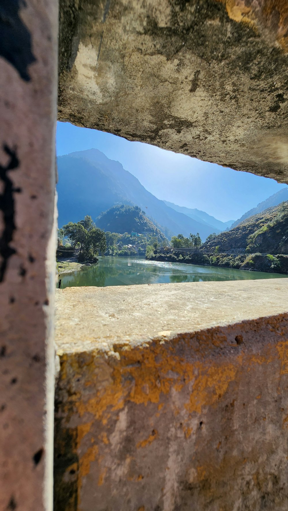 a view of a mountain lake through a hole in a wall
