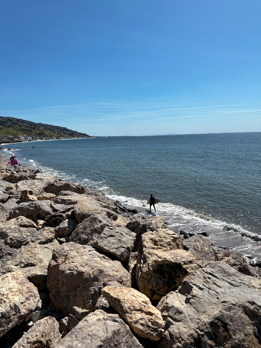 a person standing on a rocky beach next to the ocean