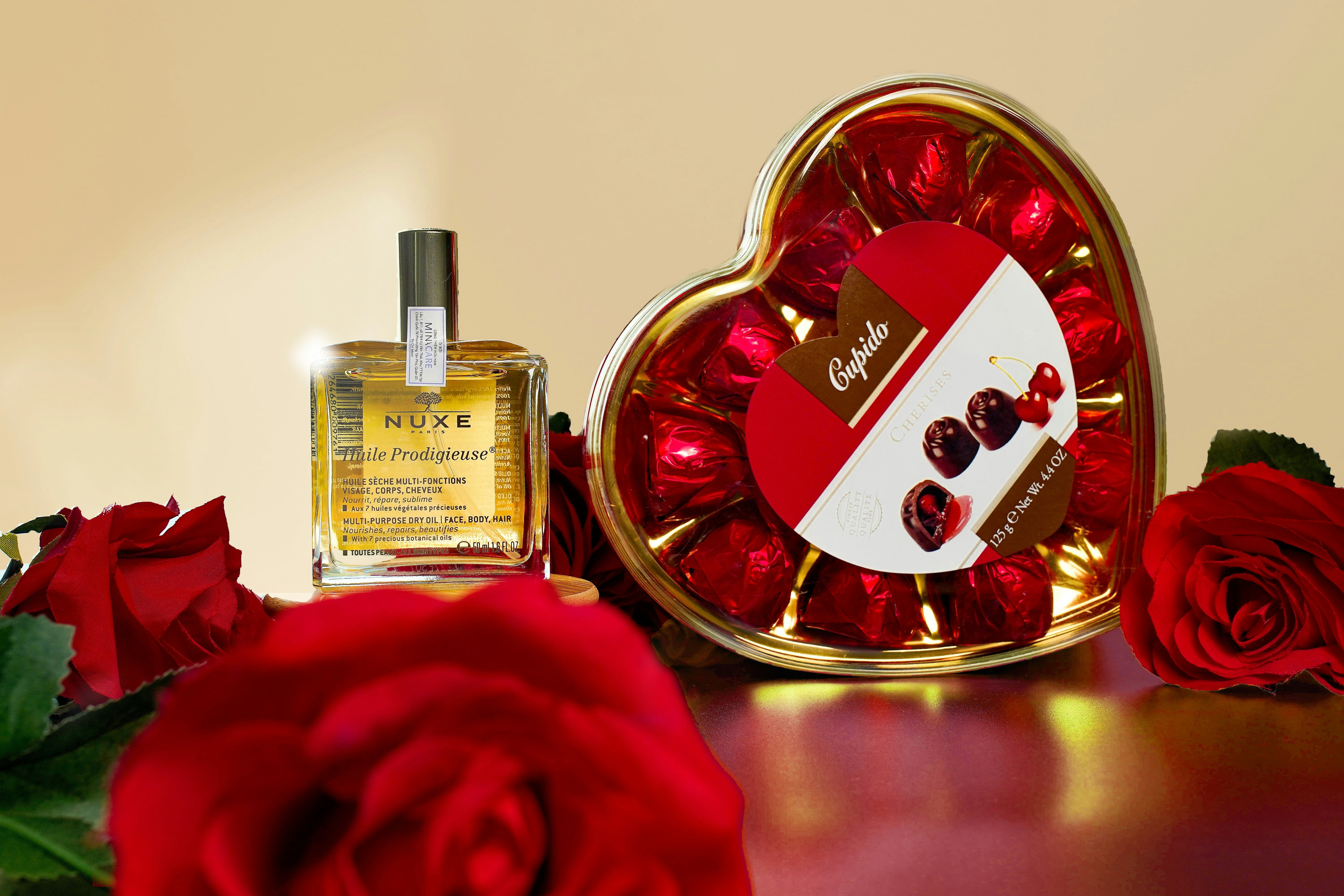 a heart shaped box with roses and a bottle of perfume
