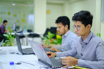 A focused virtual assistant working on a laptop in a modern office setting.