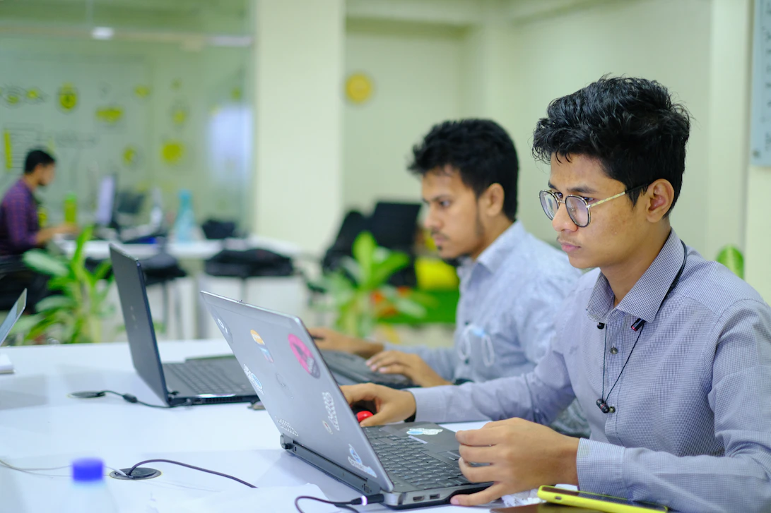 A focused team member reviewing process charts in a modern office with deep crimson and forest green accents.