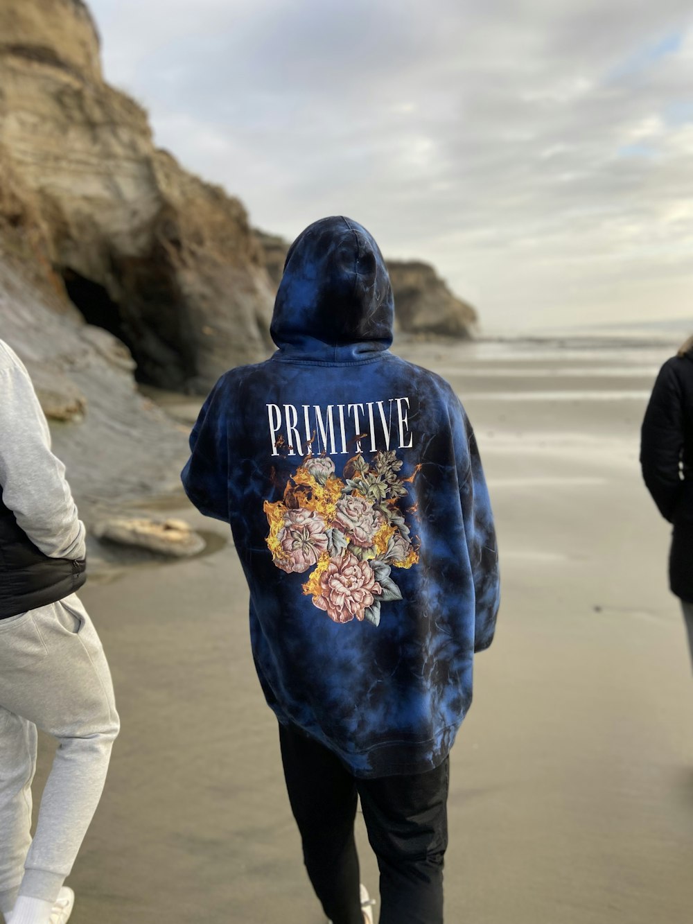 three people walking on a beach near the ocean