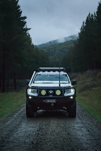 a car driving down a dirt road in the woods