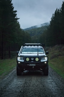 a car driving down a dirt road in the woods