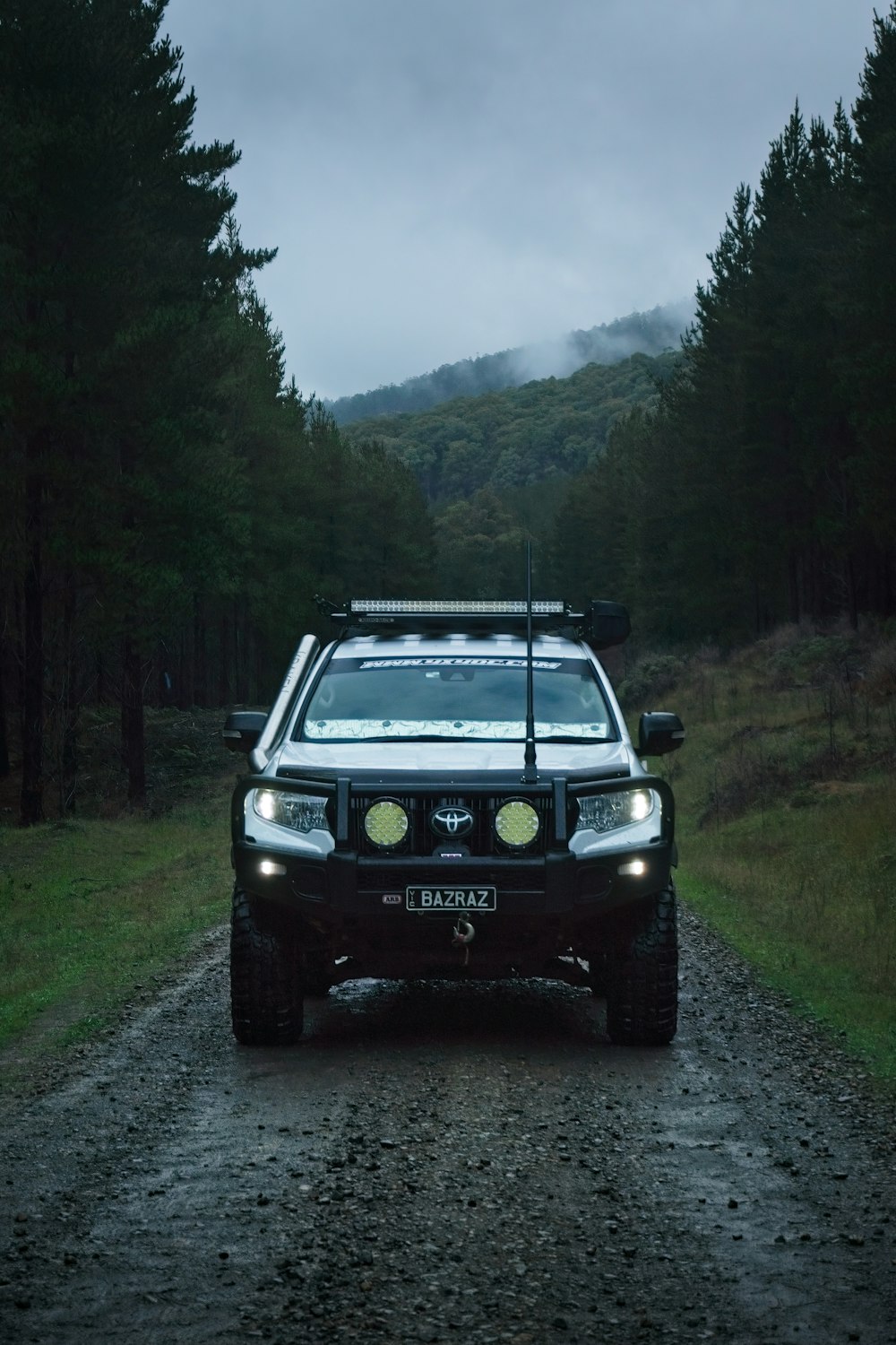 a car driving down a dirt road in the woods