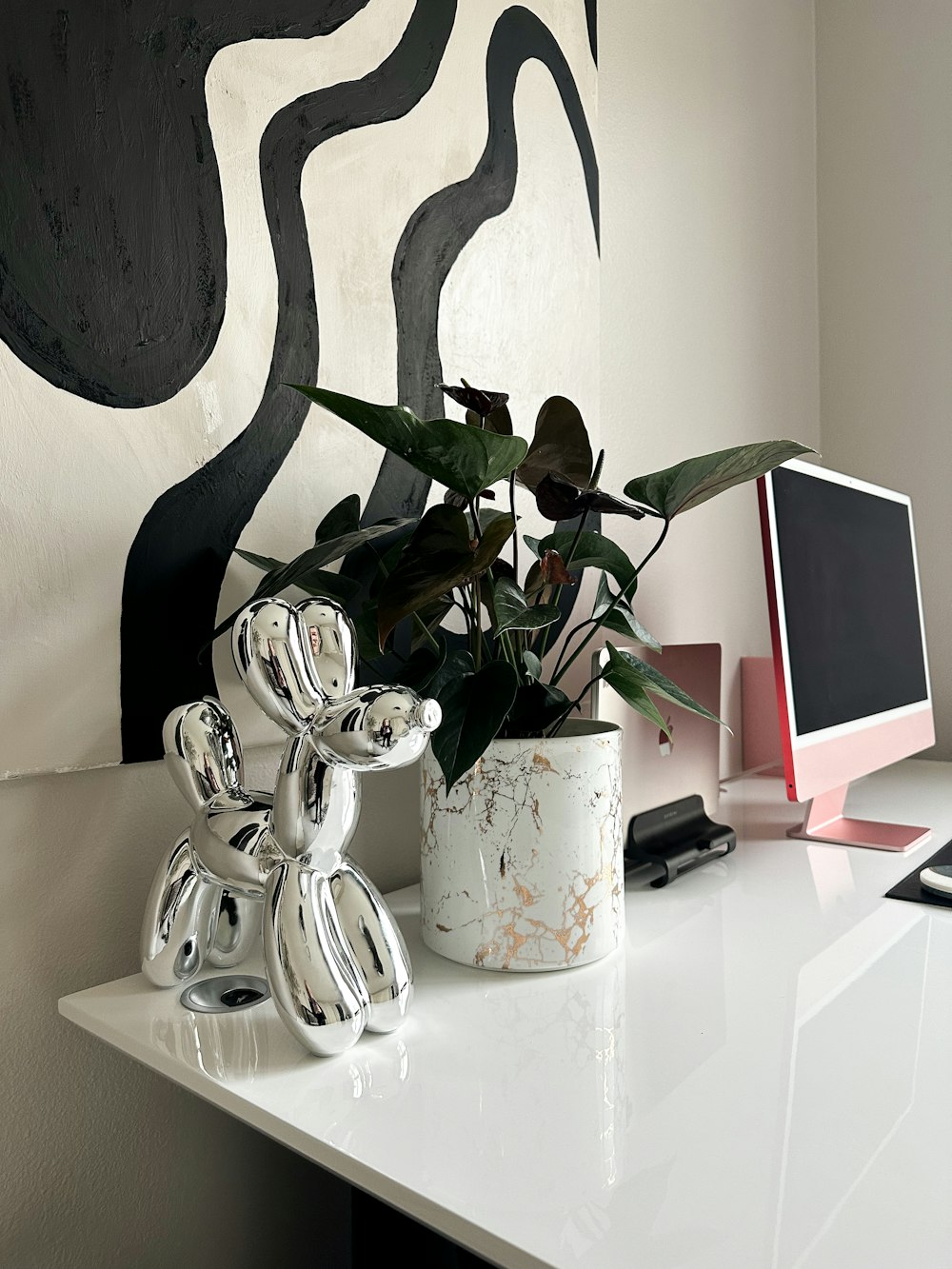 a white desk topped with a computer and a potted plant