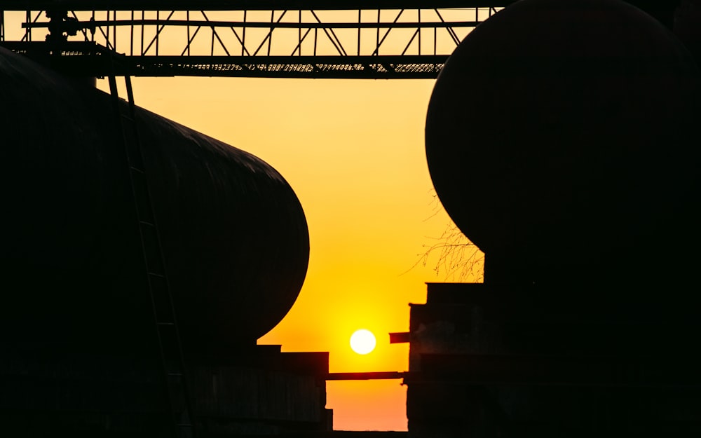 the sun is setting behind some large tanks