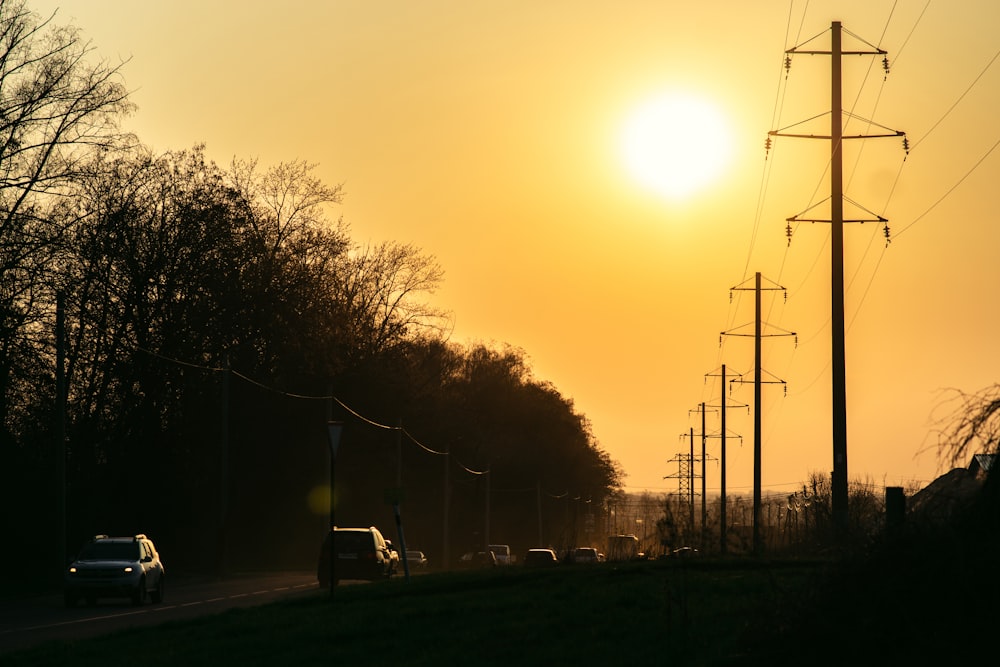 the sun is setting over a rural road