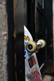 A skateboard leaning against a wall with a green and blue t-shirt draped over it