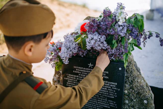 A family placing flowers at a granite monument dedicated to a fallen hero.