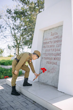 Community members placing flowers at a granite monument during a remembrance ceremony.