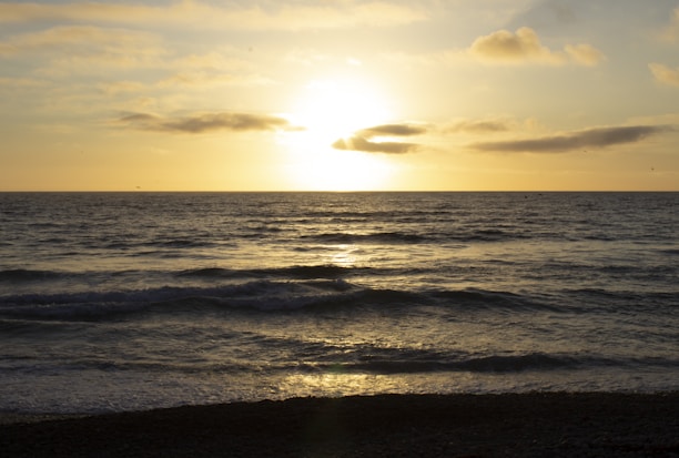 A serene ocean view at dusk with soft golden light reflecting on the water.