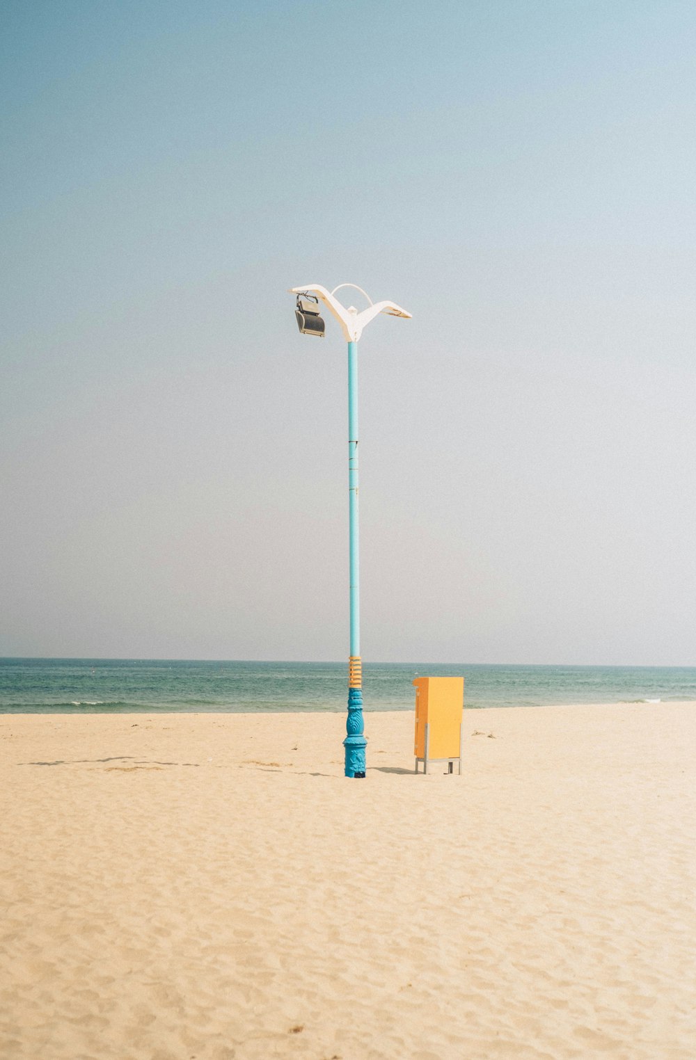 a street light sitting on top of a sandy beach