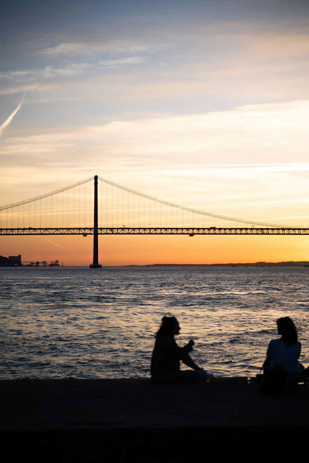 a couple of people sitting on top of a beach next to the ocean