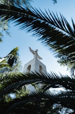 Statue of Shakira in Barranquilla surrounded by lush greenery and blue skies