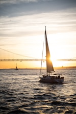 a sailboat in the water with a bridge in the background