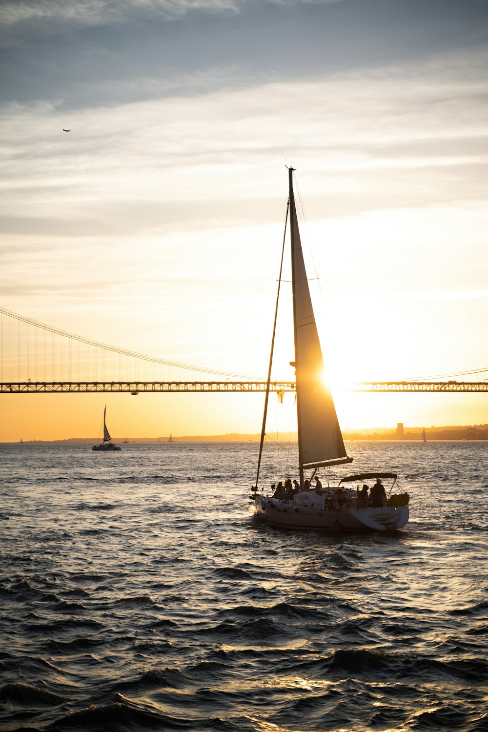 a sailboat in the water with a bridge in the background