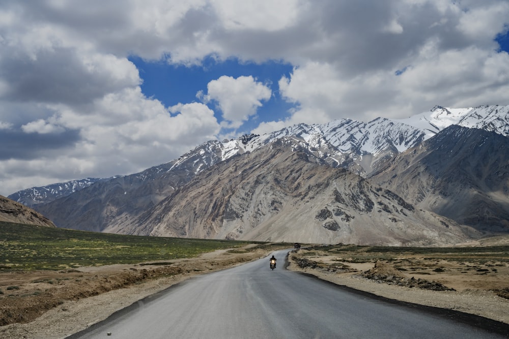 a person riding a motorcycle down a road in the mountains