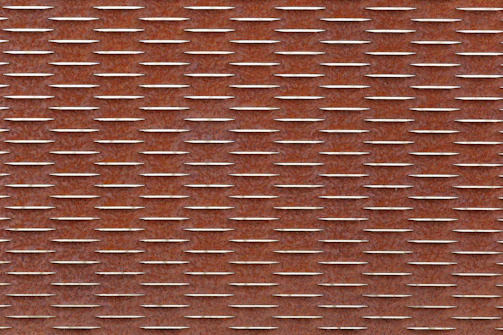 A rust-colored metal surface with a repeating pattern of raised, rectangular shapes aligned in parallel rows. The texture creates a rugged and industrial look.