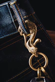 A colorful keychain with the Santa Paciencia logo resting on a denim jacket pocket.
