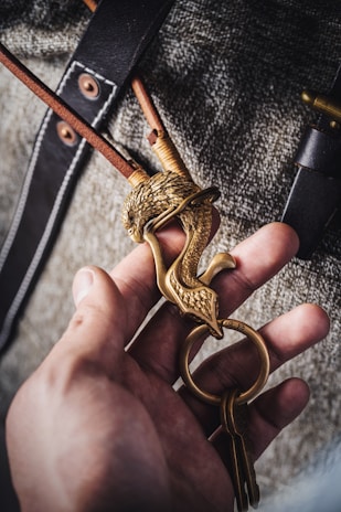 Close-up of a hand holding a minimalist leather keychain with delicate stitching.